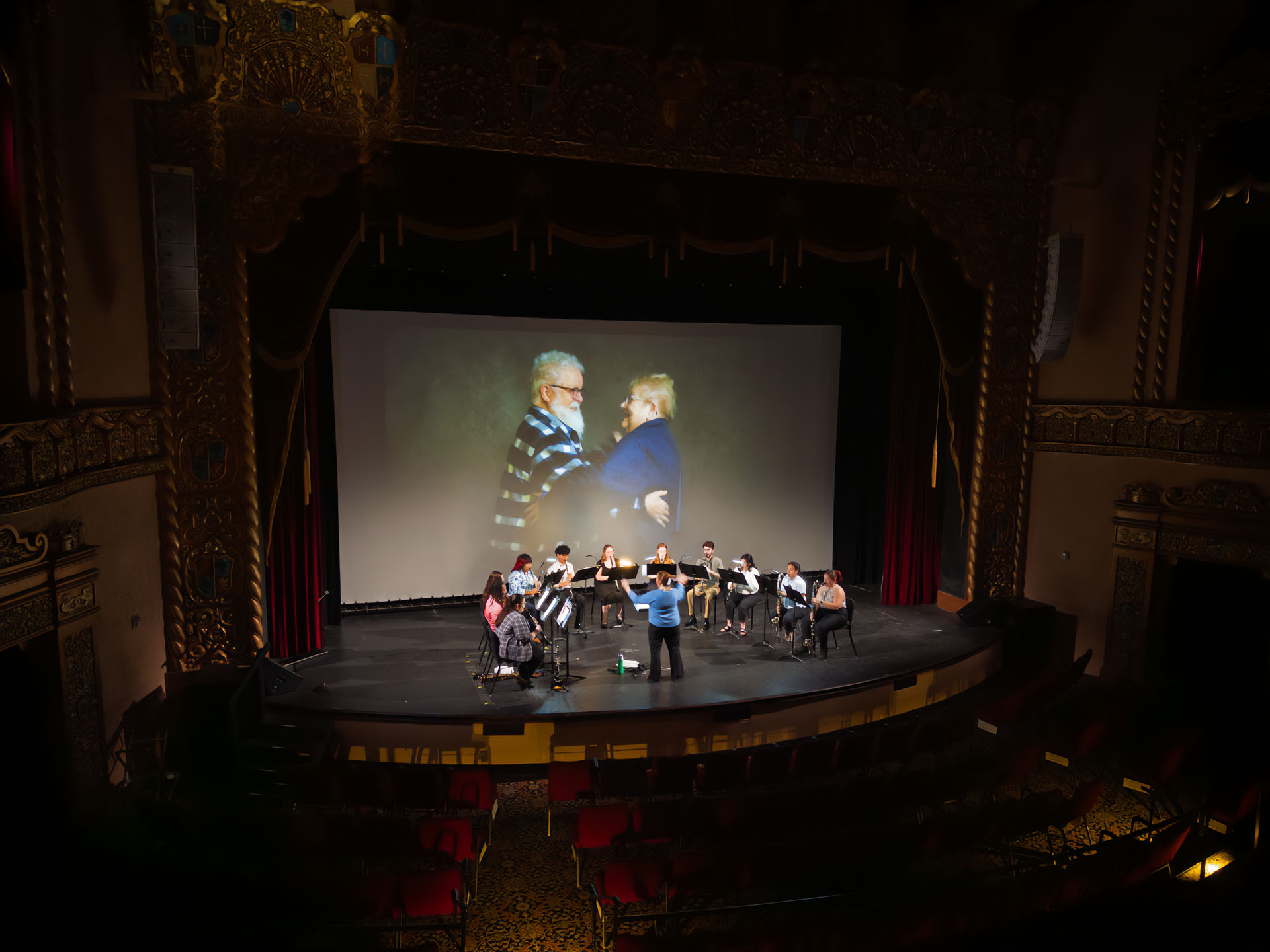 ESU ensemble playing in front of projection of long portraits on Granada Theaterstage
